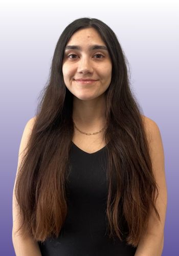 Smiling woman with long hair and purple background.