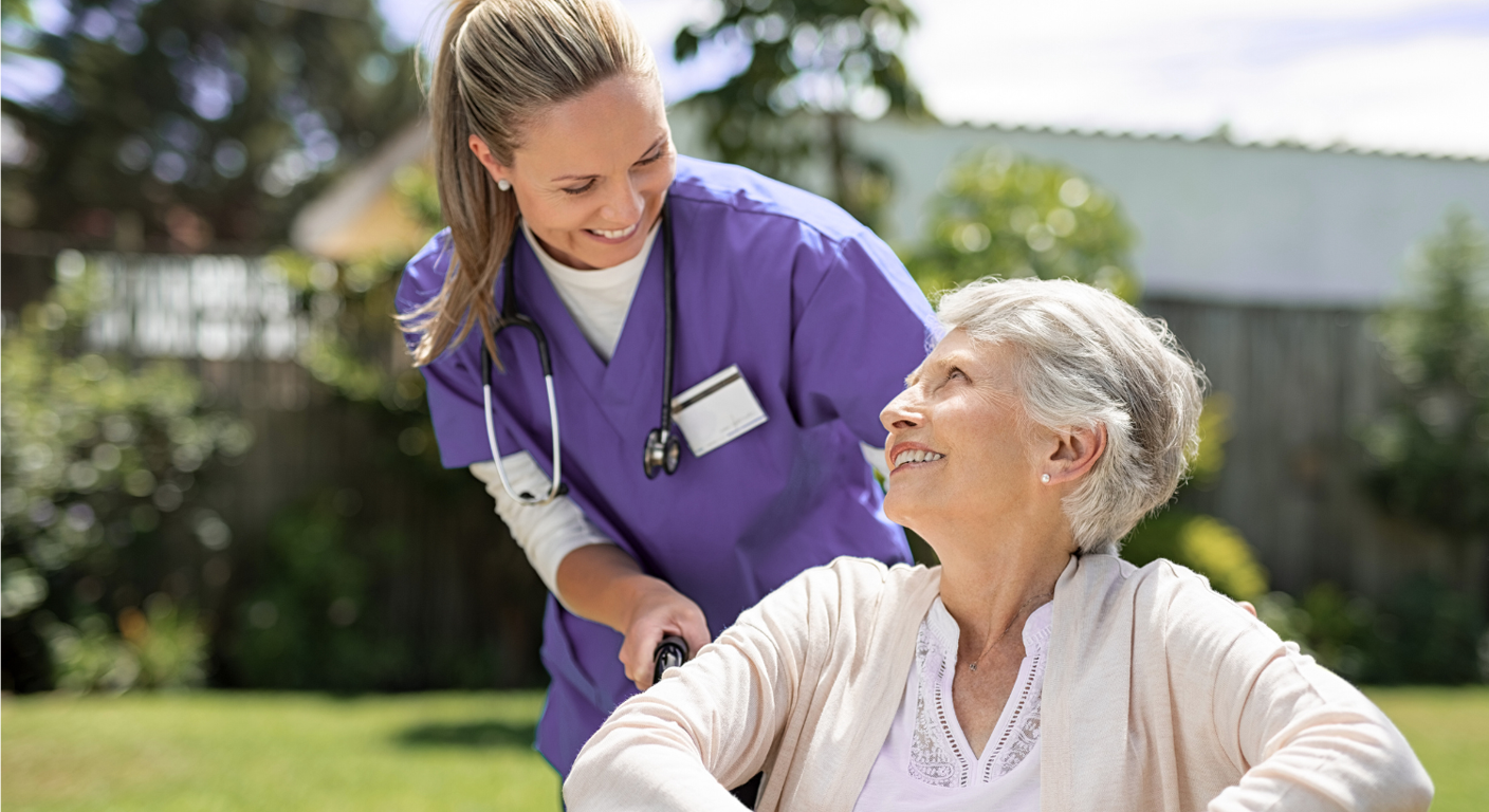 Nurse assisting elderly woman in wheelchair outside