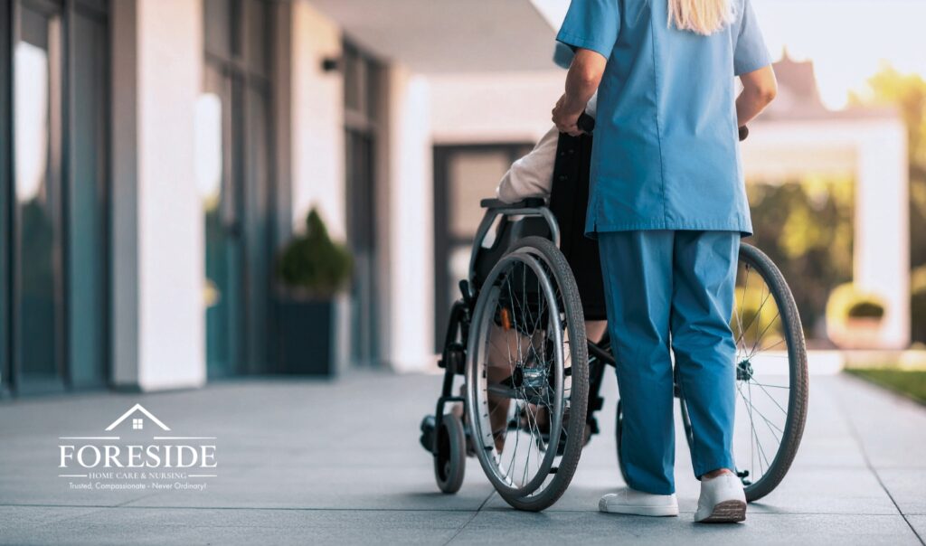 Nurse assisting person in wheelchair outdoors.