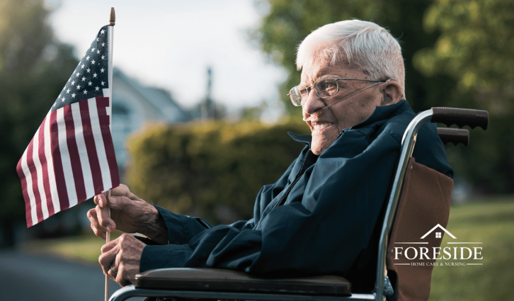 Elderly person in wheelchair holding American flag.