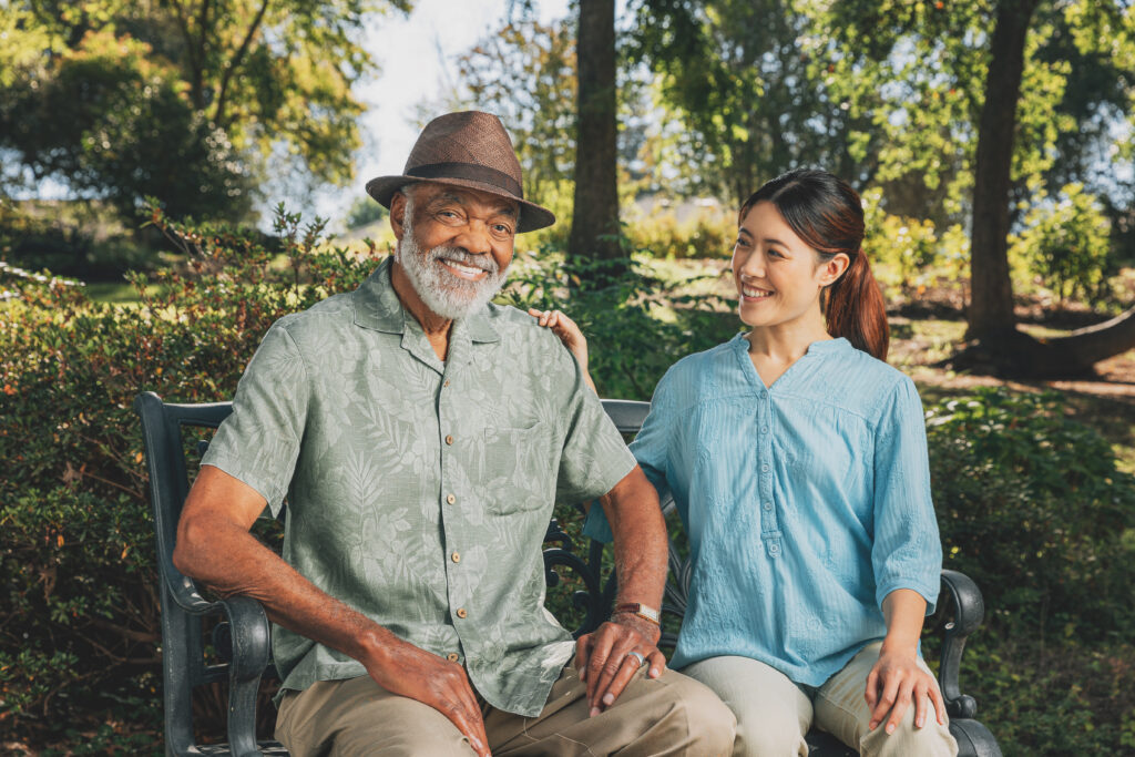 Smiling people sitting on a park bench outdoors.
