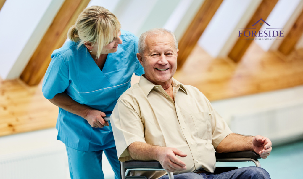 Caregiver assisting elderly man in wheelchair smiling.